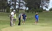 John Madsen (third from left) chips in on hole 9. - Tim Brody / Bulletin Photo