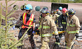 Firefighters and paramedics carry a “victim” away from the “downed aircraft:”. - Tim Brody / Bulletin Photo