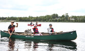 Jesse Terry (left) and his children Miali (centre) and Tevai (right), along with their dog Nibi, paddle along the shoreline of Pelican Lake as part of the Blueberry Flotilla. - Tim Brody / Bulletin Photos