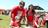 Clockwise from top left: Eric Kiepek and wife Rebecca Kiepek look on as their children Owen and Wyatt play one of the games set up by the Lions Club. - Tim Brody / Bulletin Photo