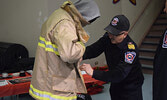 Sioux Lookout Fire Chief Rob Favot (right) helped students get decked out in full firefighting gear at the Sioux Lookout Fire Services booth. - Jesse Bonello / Bulletin Photo