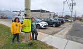 Flint and Renata Rattai stand by Sixth Avenue with a poster directing drivers to the rear of the Legion during the Legion Ladies Auxiliary’s takeout chili event.   Andre Gomelyuk/ Bulletin Photos