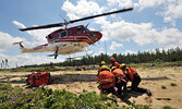 The Adam Jedrasik crew of Ontario FireRangers crouches while a helicopter departs having unloaded the crew and their equipment for a mock fire training exercise testing the team’s initial attack firefighting skills, north of Dryden June 21.   Photo courte