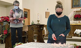 Reverend Deacon Muriel Anderson (left) reads out names of area residents departed in the past year while Church Warden Rikki Burke (right) lights candles in their memory at St. Mary’s Anglican Church during this year’s Ice Candle Memorial Service.   Tim B