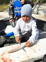 School student Gage Wabano using his skills developed during the program to cut the fish. - Waninitawingaang Memorial School / Submitted Photos