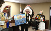 Lac Seul First Nation Chief Clifford Bull (left) presents Lac Seul Police Service Chief of Police Bruno Rossi (centre) and his wife Nicki Rossi (right) with welcoming gifts, which included a Don Ningewance painting. Tim Brody / Bulletin Photo
