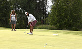 Gerson Agustin putts in while Christy McIntomney looks on. - Tim Brody / Bulletin Photo