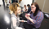 Drama club students prepare for their roles in the training exercise.  Samantha Wood (right) applies make-up to the face of Rhyonna Delpesche to make her appear injured. - Tim Brody / Bulletin Photo