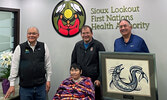 From left: SLFNHA CEO and President James Morris and Acting SLFNHA Board Chair Howard Meshake present Fort William First Nation Chief Peter Collins with a framed gift. Front: Jeannie Carpenter, wife of Howard Meshake.     SLFNHA / Submitted Photo