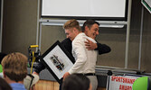 Kendall Schulz (right), along with other members from the boys hockey team, present head coach Karl Schulz (left) with a signed team photo to commemorate the 2018-19 season. - Jesse Bonello / Bulletin Photos